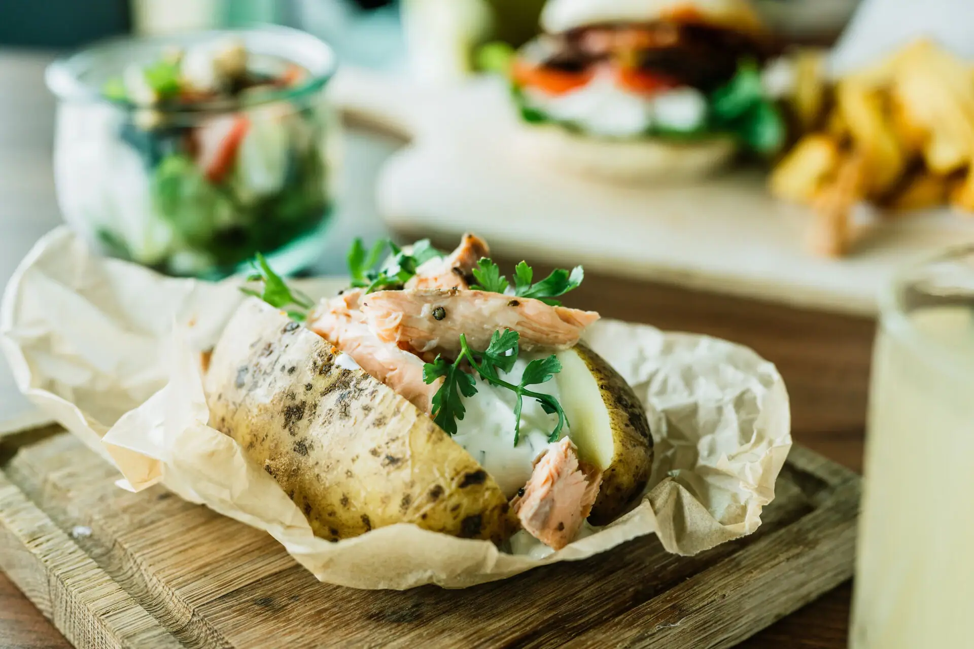 Ofenkartoffel Gebackene Kartoffel mit Fleisch und Grünzeug auf einem Holzbrett