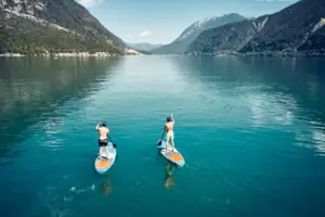 Achensee Zwei Männer auf Paddleboards auf einem See.
