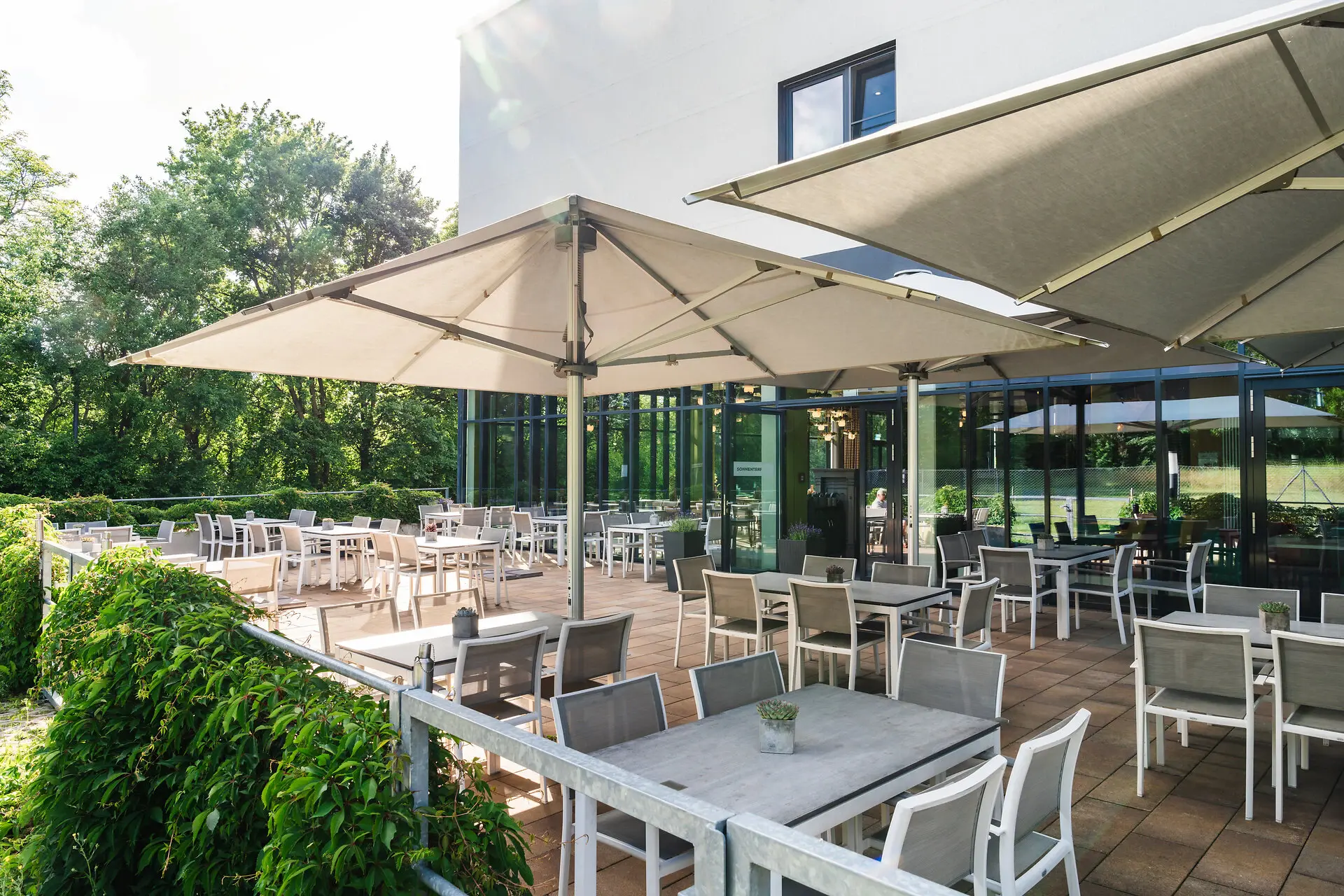 Terrasse im aja Bad Saarow Eine Terrasse mit Tischen und Stühlen.