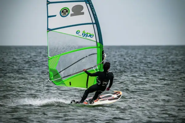 Eine Person auf einem Surfbrett mit Segel.