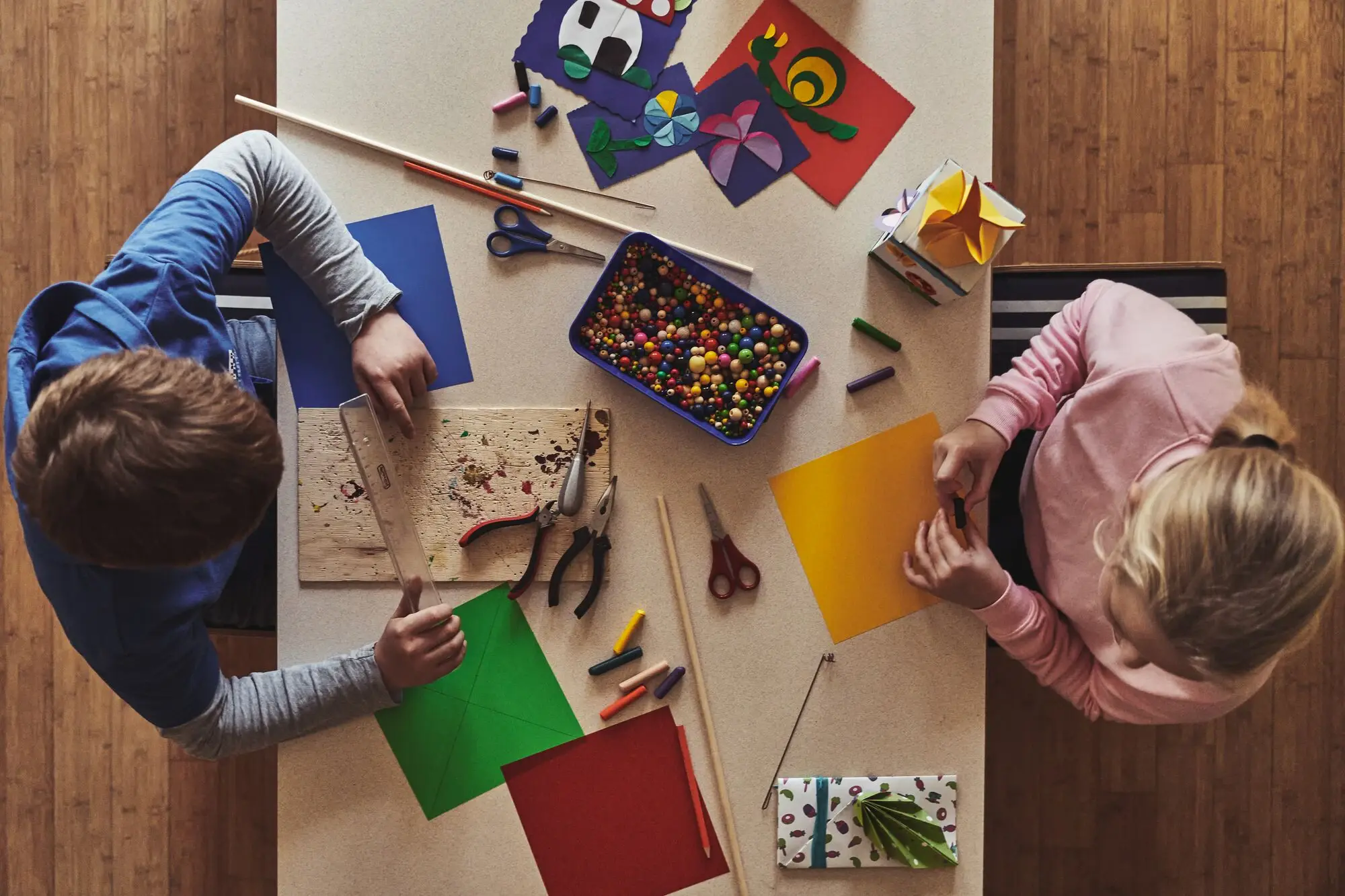 Kinderclub aja Bansin Zwei Kinder sitzten an einem Tisch und beschäftigt sich mit Papier und Bastelmaterialien in einem Innenraum.