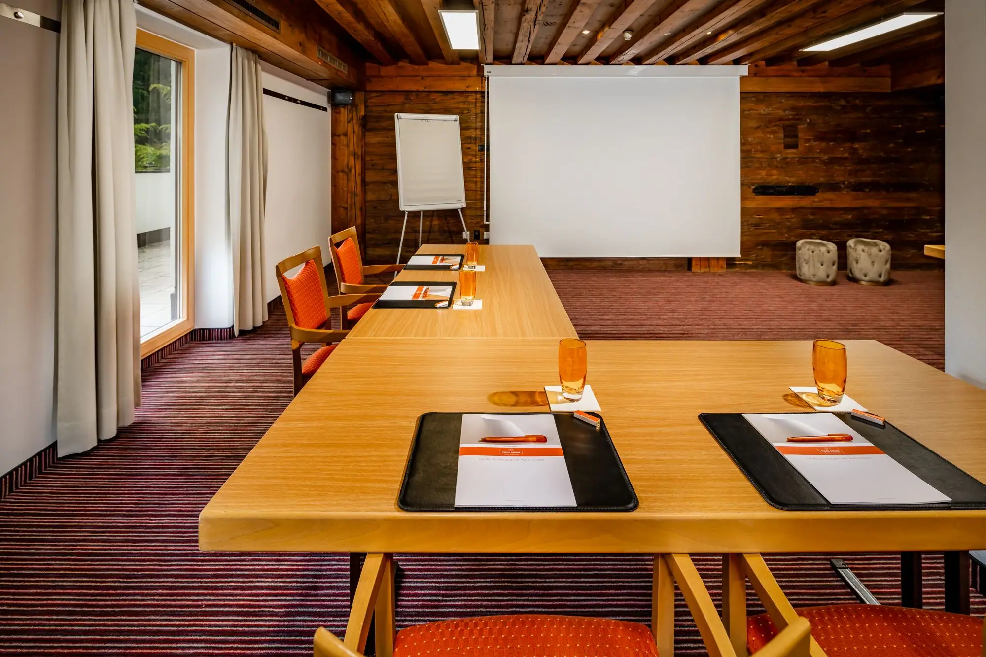 Meetingraum Ein Raum mit einer großen weißen Leinwand und mehreren Tischen.