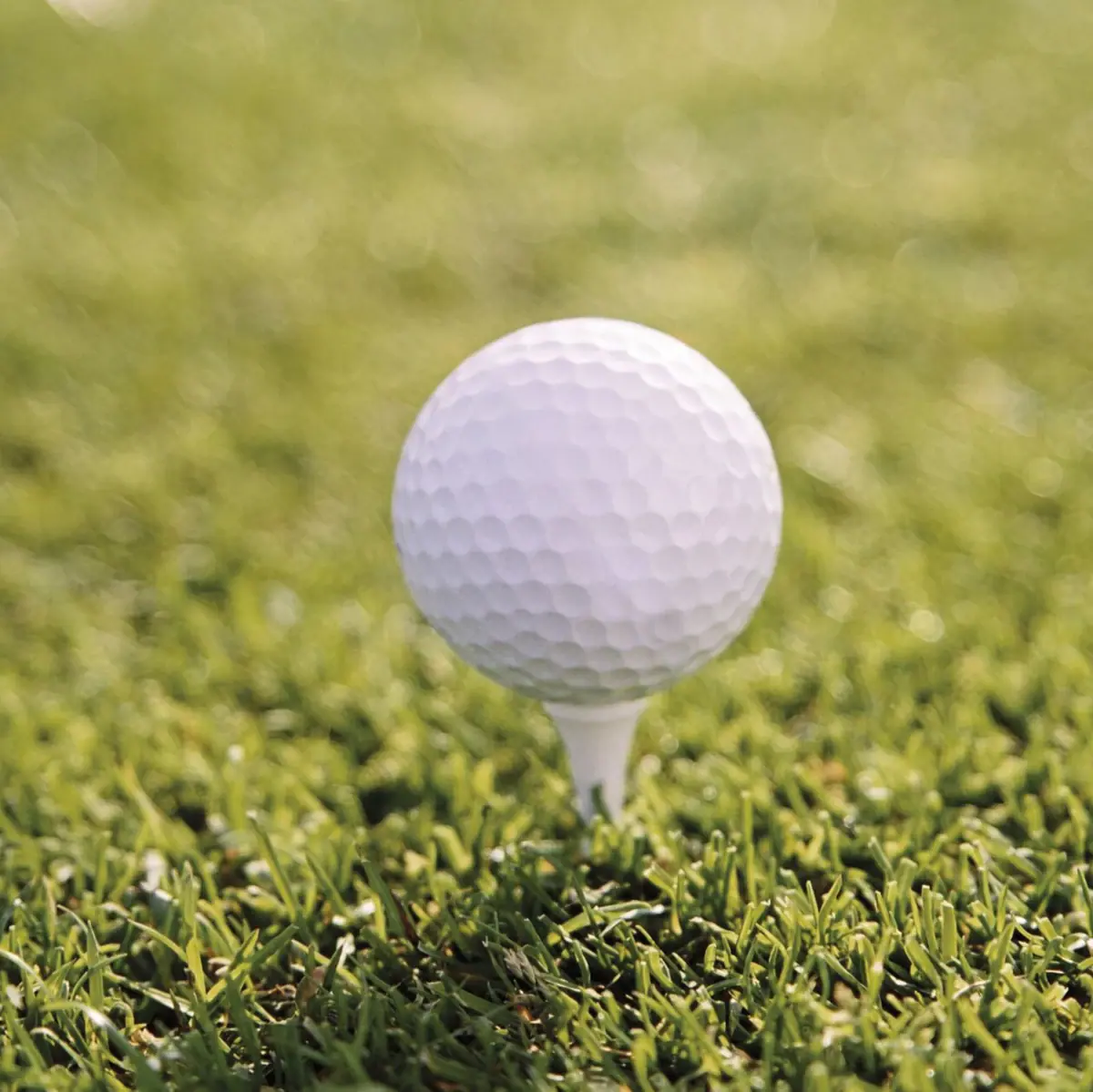 Golfurlaub Golfball auf einem Tee im Gras auf einem Golfplatz.