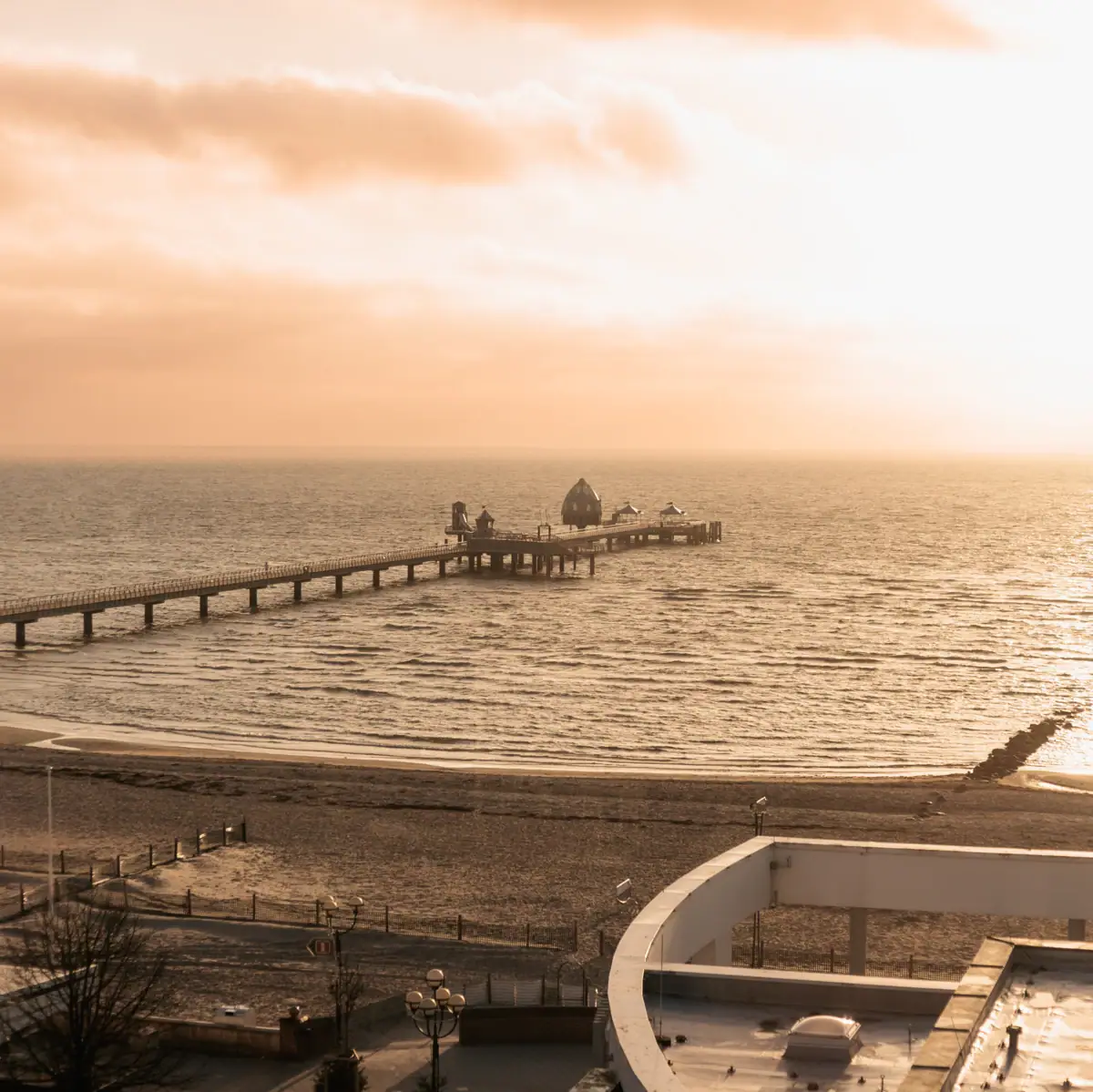 Seebrücke Grömitz Langer Pier im Wasser unter bewölktem Himmel.