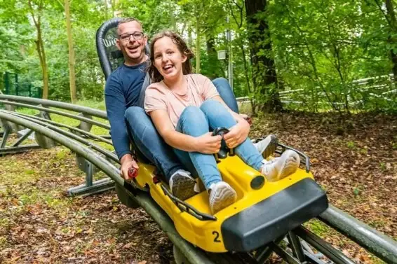 Scharmützelbob Ein Mann und eine Frau auf einer Achterbahn, beide lächeln.