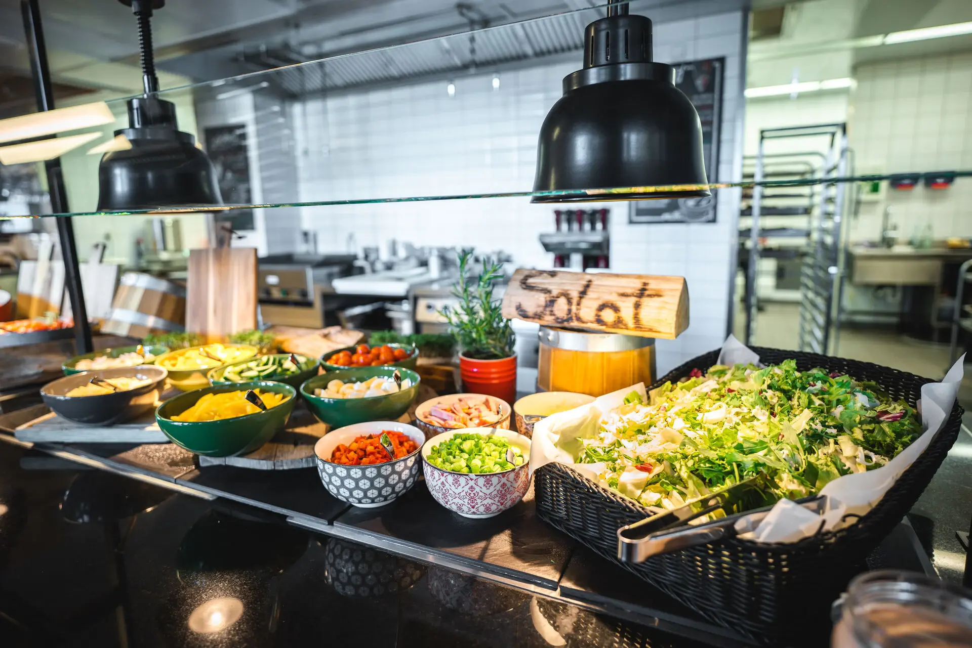 Eine Salatbar eines Buffets mit vielen verschiedenen Sorten an Salat und Gemüse wie Mais, Tomaten und Zwiebeln.