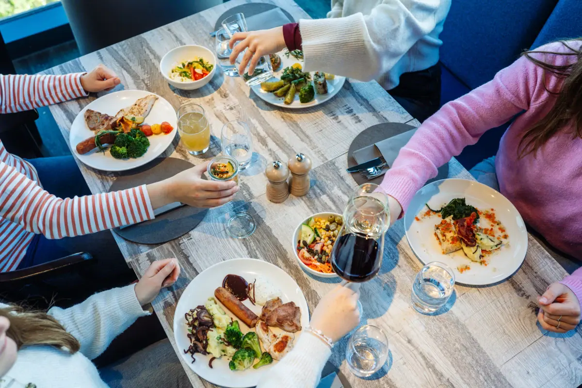 Abendessen Eine Gruppe von Menschen sitzt an einem Tisch mit Tellern voller Essen.