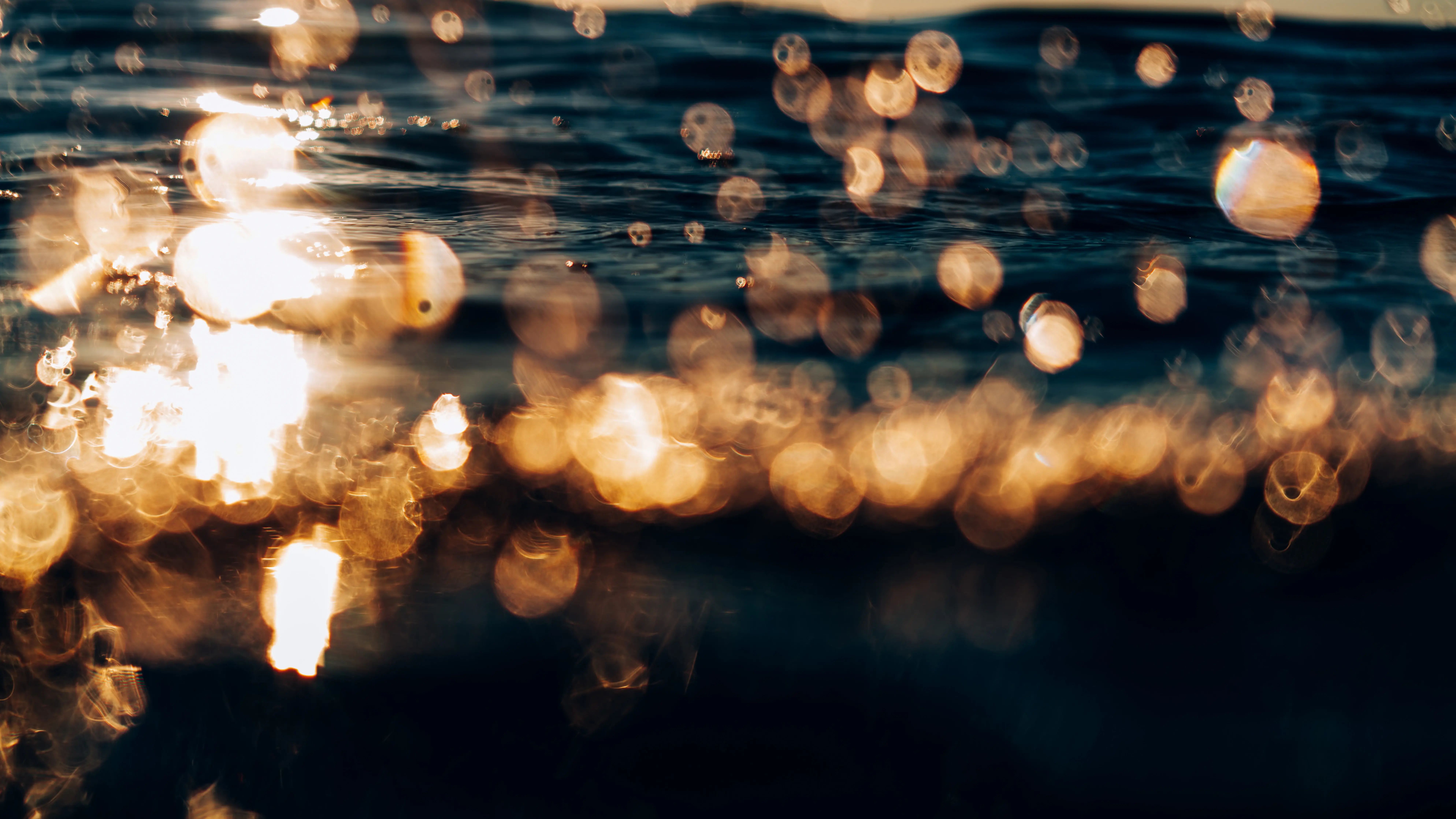 Die Sonne Glitzer in goldenen Reflexionen auf tief blauer Wasseroberfläche.