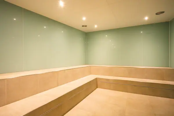 Ein Raum mit einer Bank und Leuchten, gefliestem Boden und Marmorwänden.