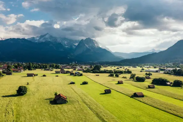Tal Grünes Feld mit Gebäuden und Bergen im Hintergrund.