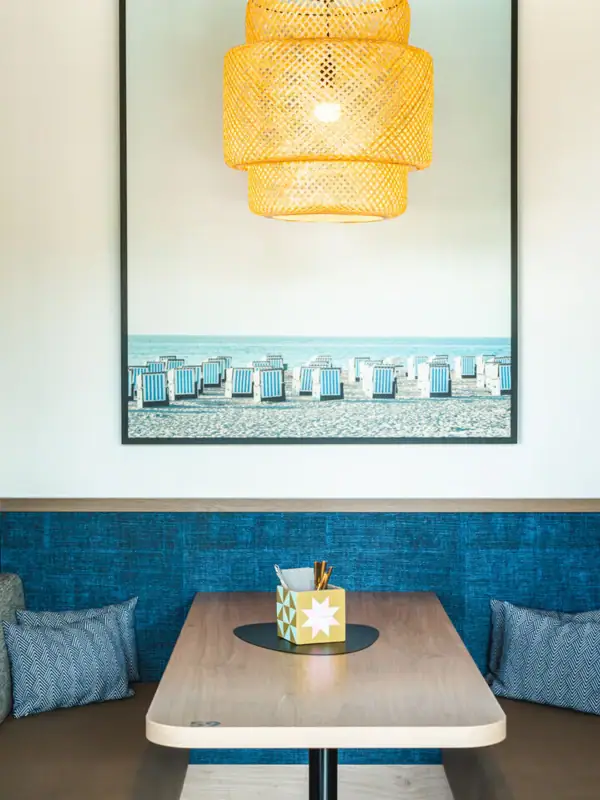 Bar im aja Warnemünde Ein Tisch mit einer Deckenlampe.