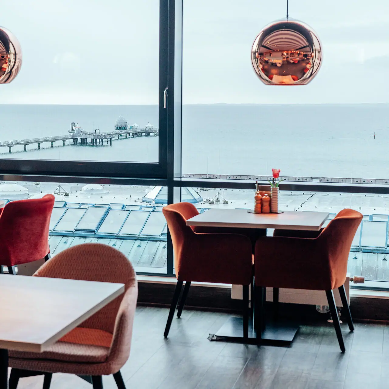 Restaurant Ein Raum mit Blick auf den Ozean und einen Pier, mit einem Kaffeetisch im Vordergrund.
