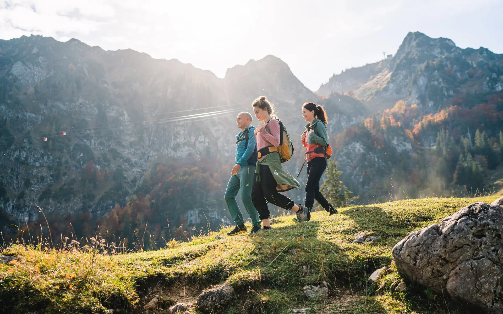 Wandern in Ruhpolding Eine Gruppe von Personen, die auf einem Hügel spazieren gehen, mit Bergen im Hintergrund.