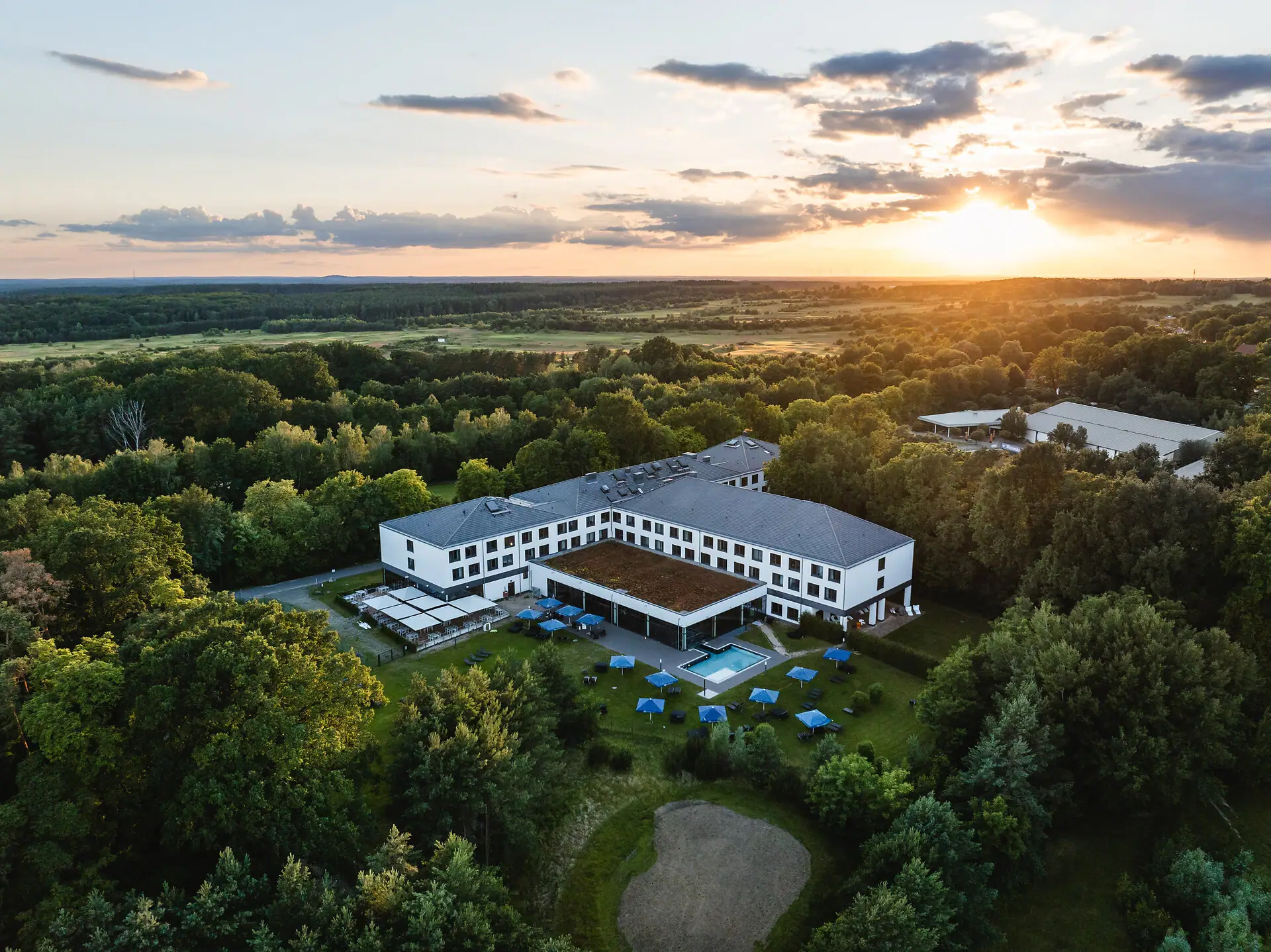 aja Bad Saarow Ein Gebäude mit einem Pool, umgeben von Bäumen.