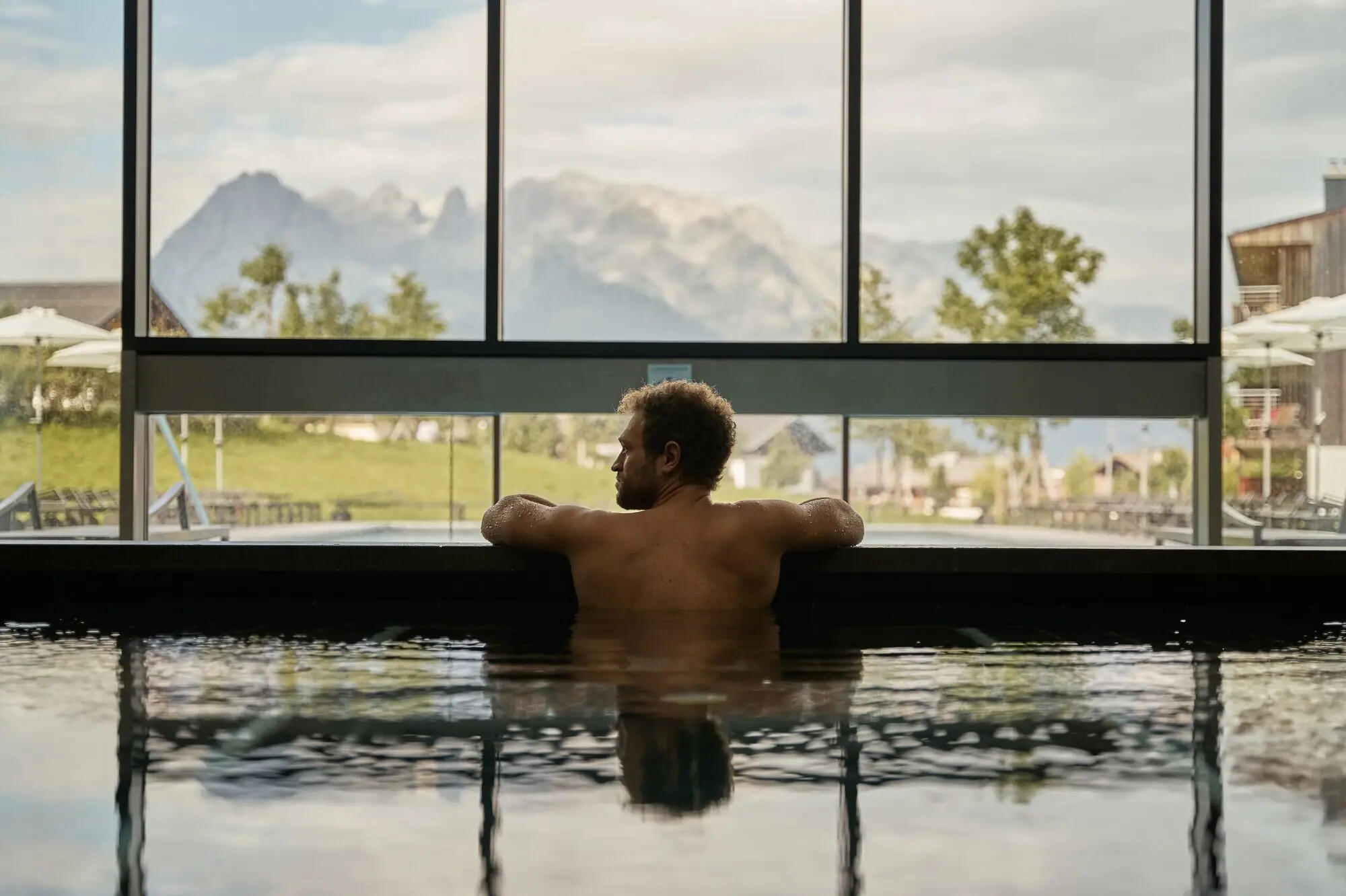 Innenpool aja Werfenweng Mann schwimmt in einem Pool mit Berg- und Baumblick.