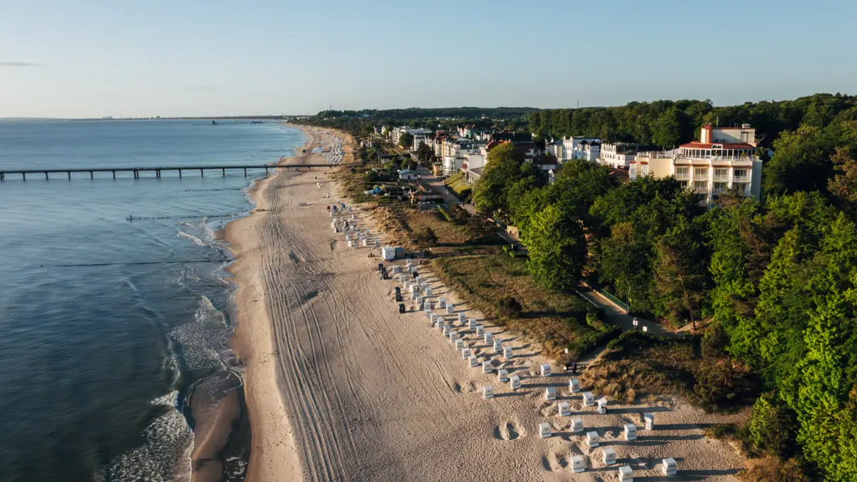 aja Strandhotel Bansin Strand mit Gebäuden und Bäumen im Vordergrund.
