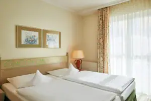 Doppelzimmer landseitig Ein Zimmer mit zwei Betten und einer Lampe.