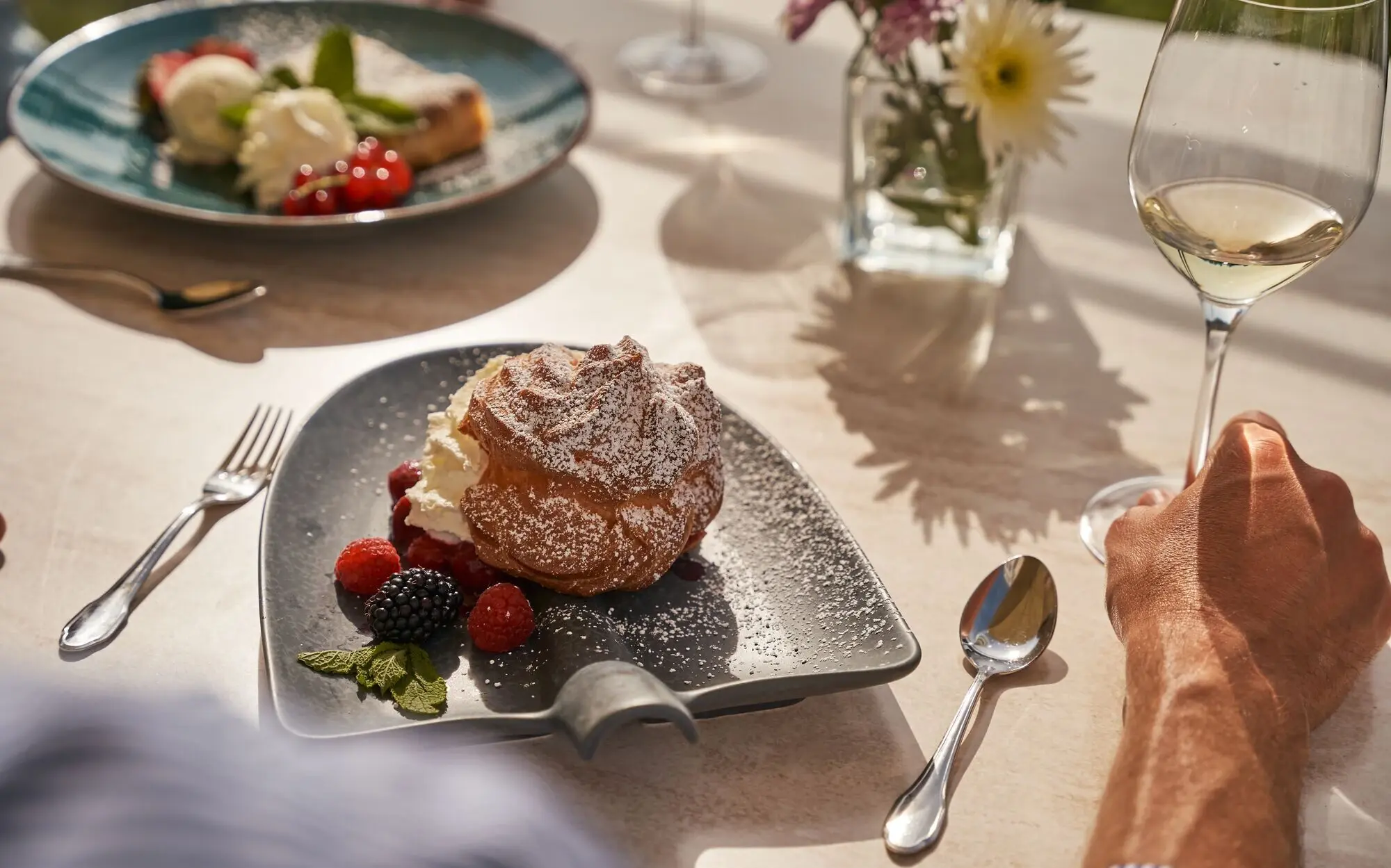 Ein Teller mit Dessert und Beeren neben einem Glas Wein.