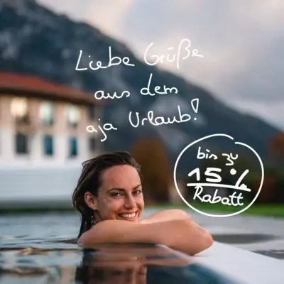 aja Frühlingswochen Eine lächelnde Frau im Pool vor einem Gebäude.