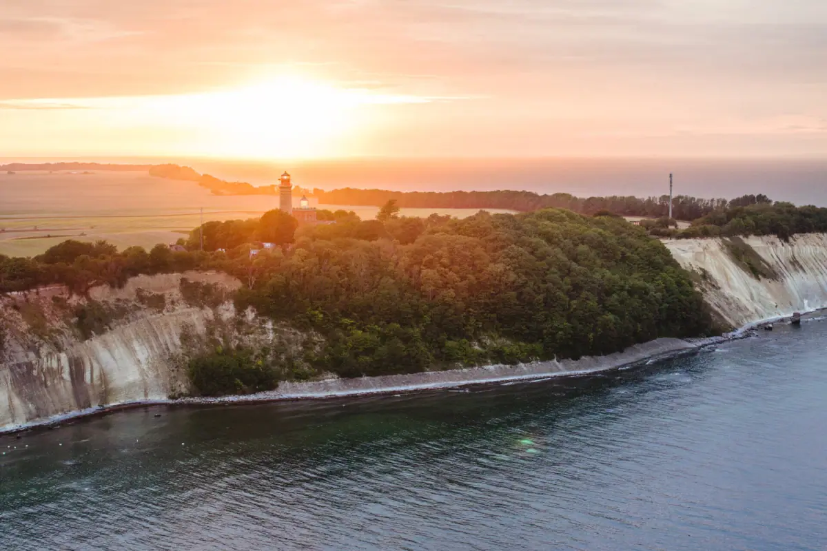 Kap Arkona Ein Gewässer mit einem Leuchtturm auf einem Hügel.