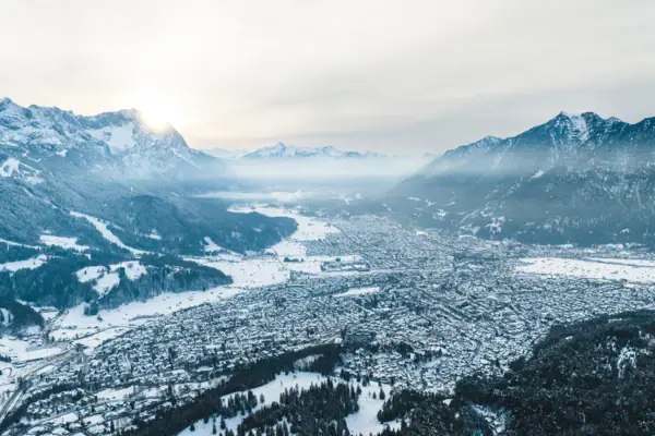 Anreise Flugzeug Schneebedeckte Stadt mit Berglandschaft im Hintergrund.