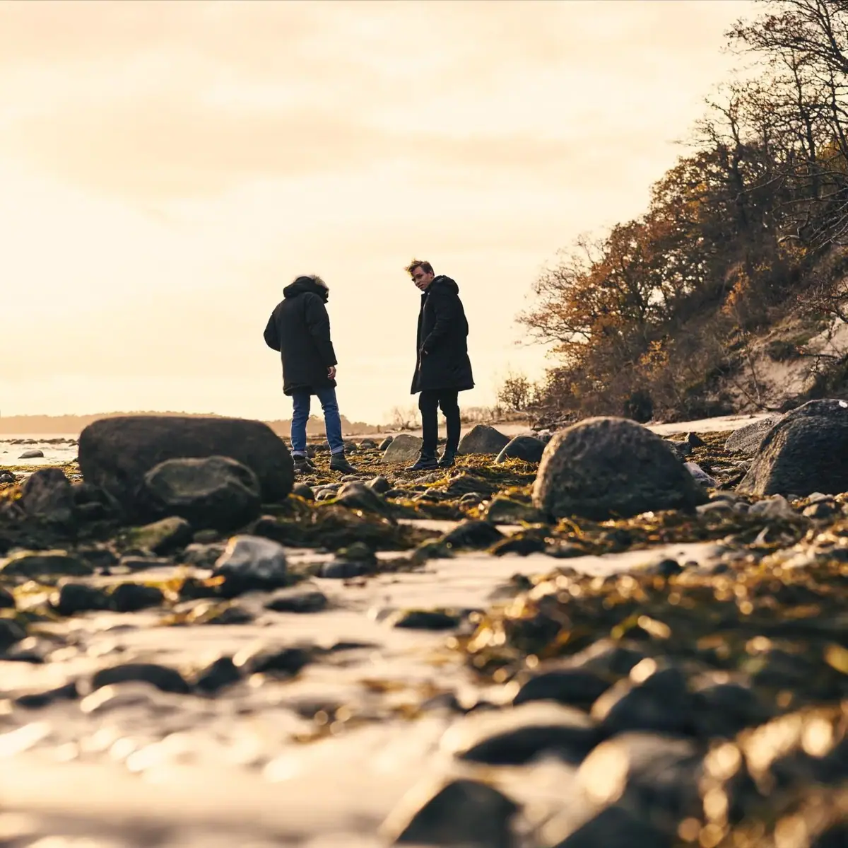 Herbst am Strand Ein Paar steht auf einem felsigen Strand.