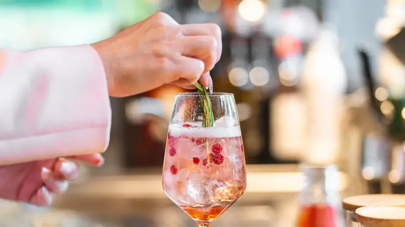 Aperitif Eine Person legt ein Blatt auf ein Getränk in einem Weinglas.