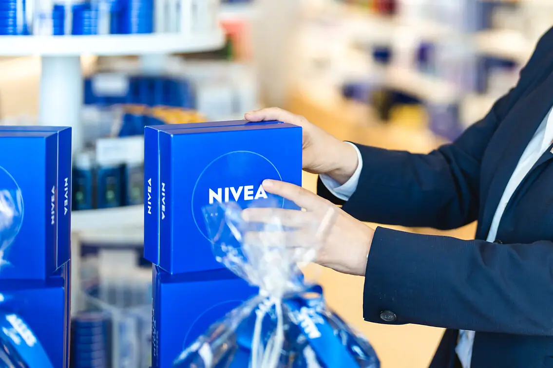 Eine Frau im Anzug hält eine Schachtel von NIVEA
