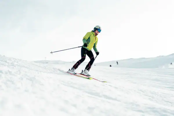 Skifahren Eine Person fährt auf Skiern einen verschneiten Hang hinunter.