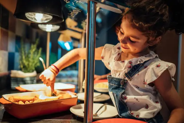 Kinderbuffet Mädchen in Latzhose und weißem Hemd