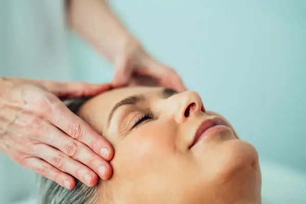 Kosmetik Eine Person massiert den Kopf einer Frau.