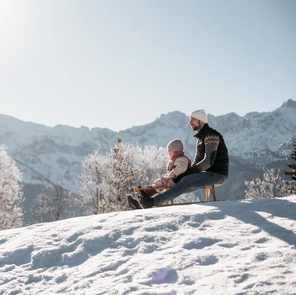 Schlittentour Ein Mann und ein Kind sitzen auf einer Bank im Schnee.