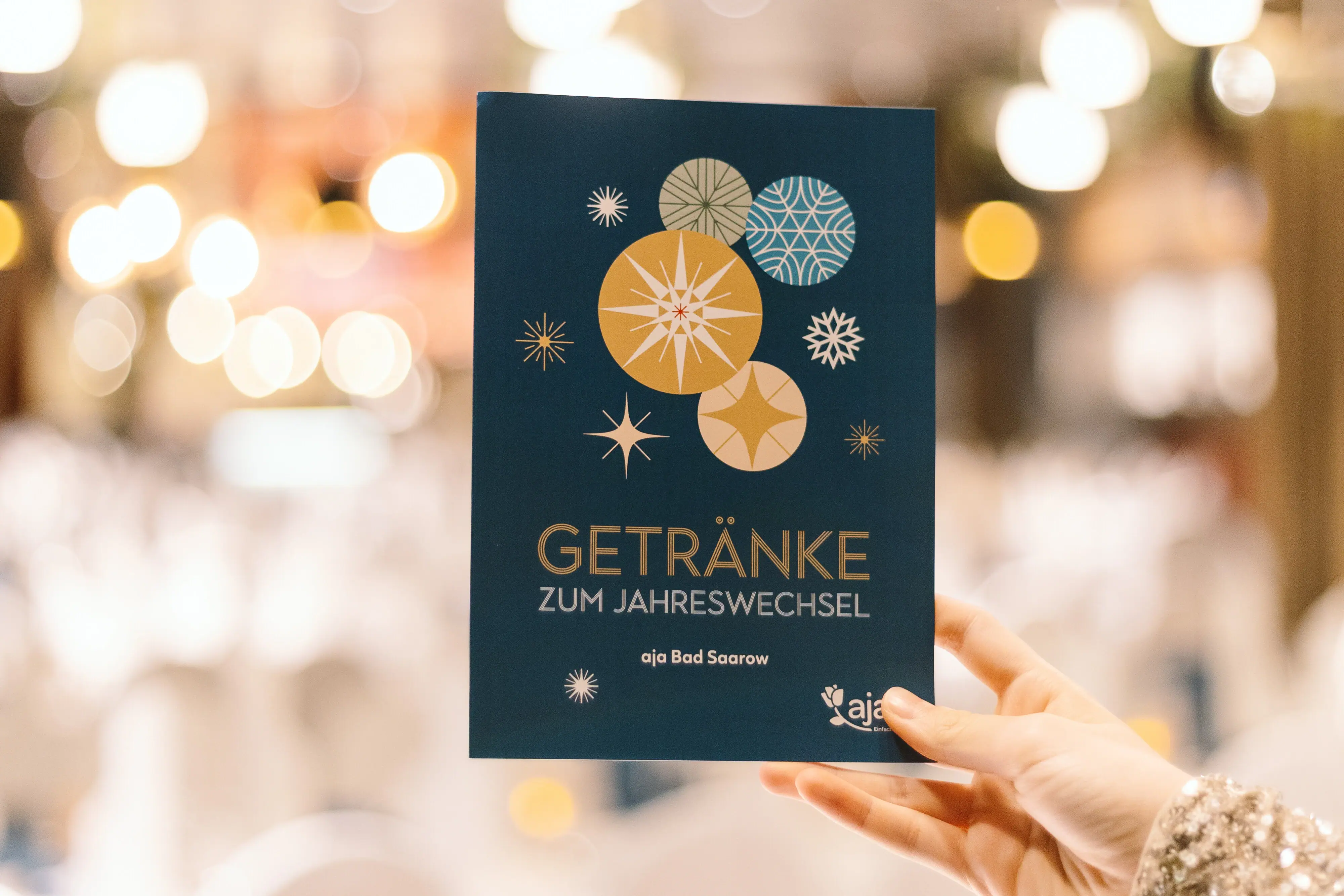 Silvesterangebot im aja Bad Saarow Hand hält eine blaue Karte auf der Getränke steht
