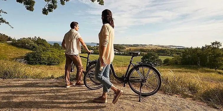 Ein Mann und eine Frau stehen neben Fahrrädern im Freien. Ein Mann und eine Frau stehen neben Fahrrädern im Freien.