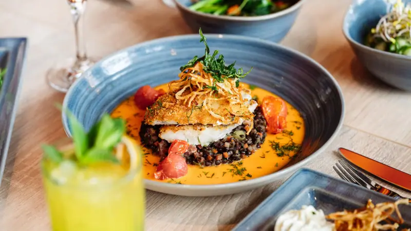 Fischgericht Ein Teller mit Essen auf einem Tisch.