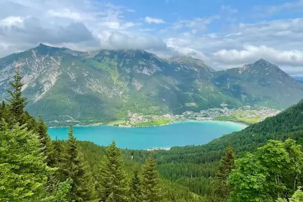 Blick auf den Achensee Ein See umgeben von Bäumen und Bergen.