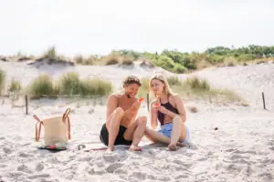 Warnemünde Strand Ein Mann und eine Frau sitzen am Strand und essen Wassermelone.