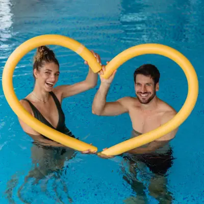 Aqua Fitness Ein Mann und eine Frau halten ein gelbes, herzförmiges Rohr.