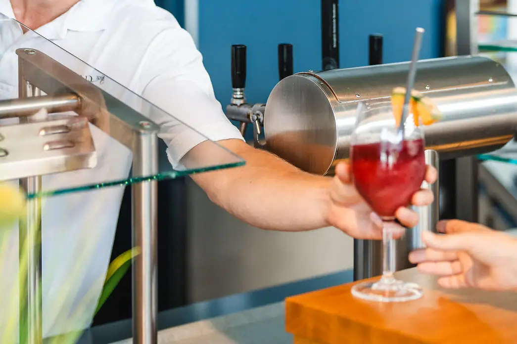 Poolbar Ein Mann reicht einem Kunden ein Getränk.