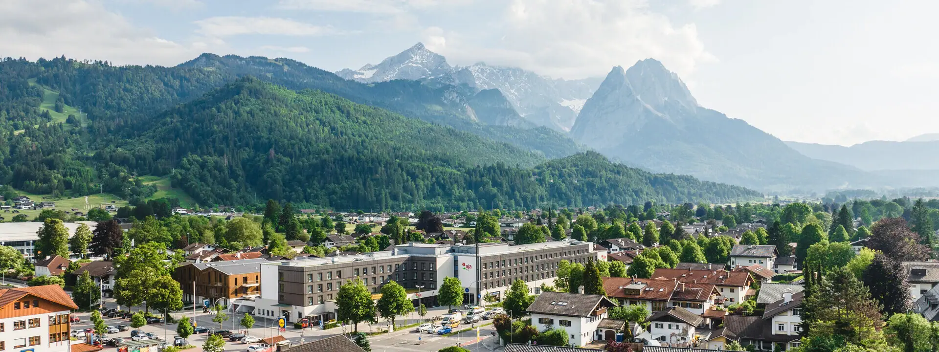 aja Garmisch-Partenkirchen Eine Stadt mit vielen Gebäuden und Bäumen, im Hintergrund Berge.