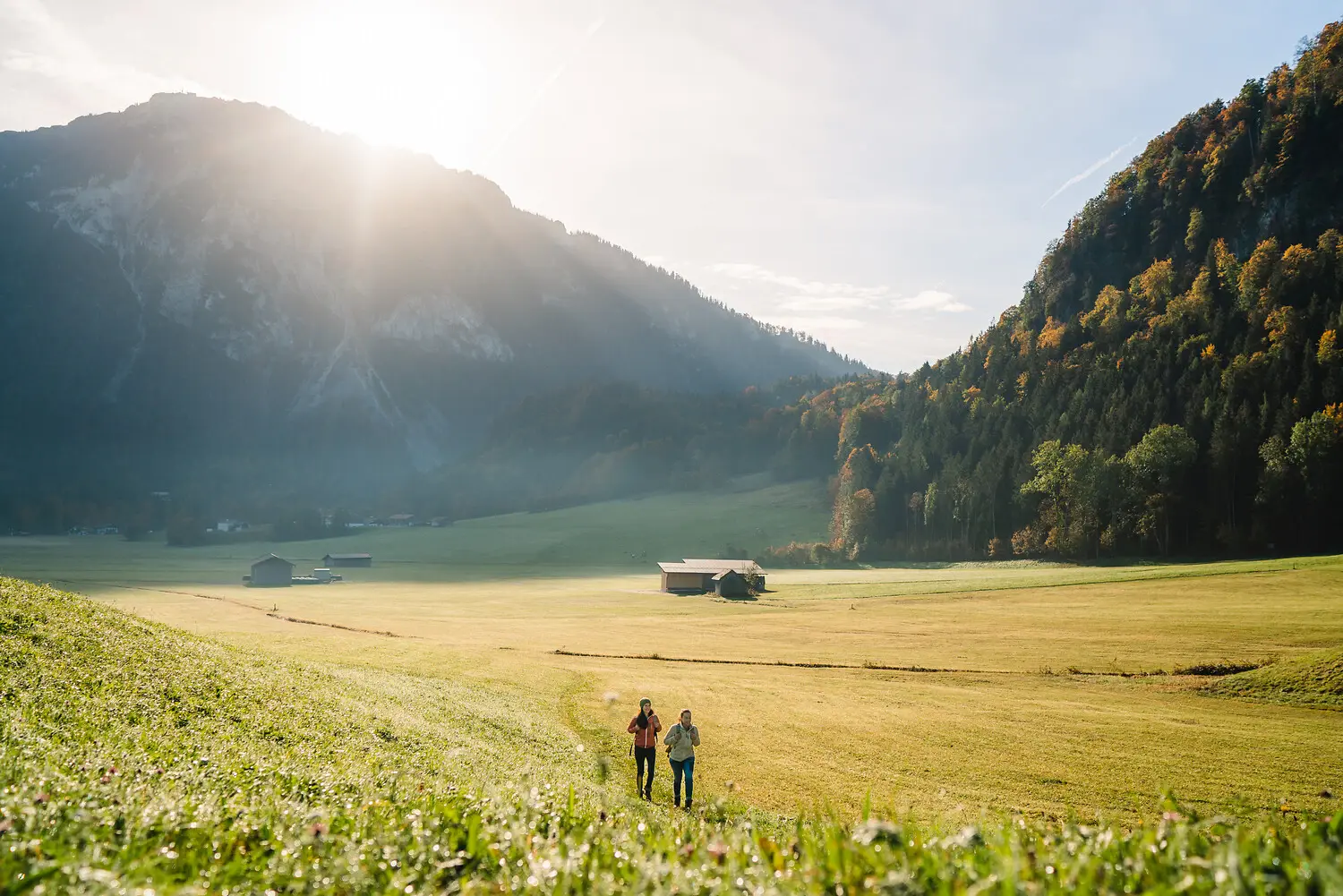 Ruhpolding im Herbst Personen laufen in einem Feld mit Bergen im Hintergrund.