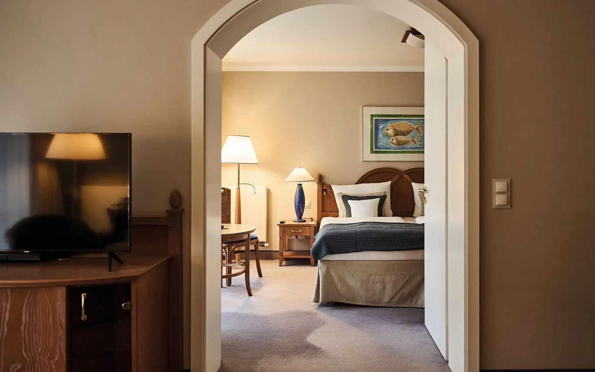 Senior-Suite aja Bansin Ein Schlafzimmer mit einem Bett und einem Nachttisch, dazu ein Spiegel und eine Kommode.