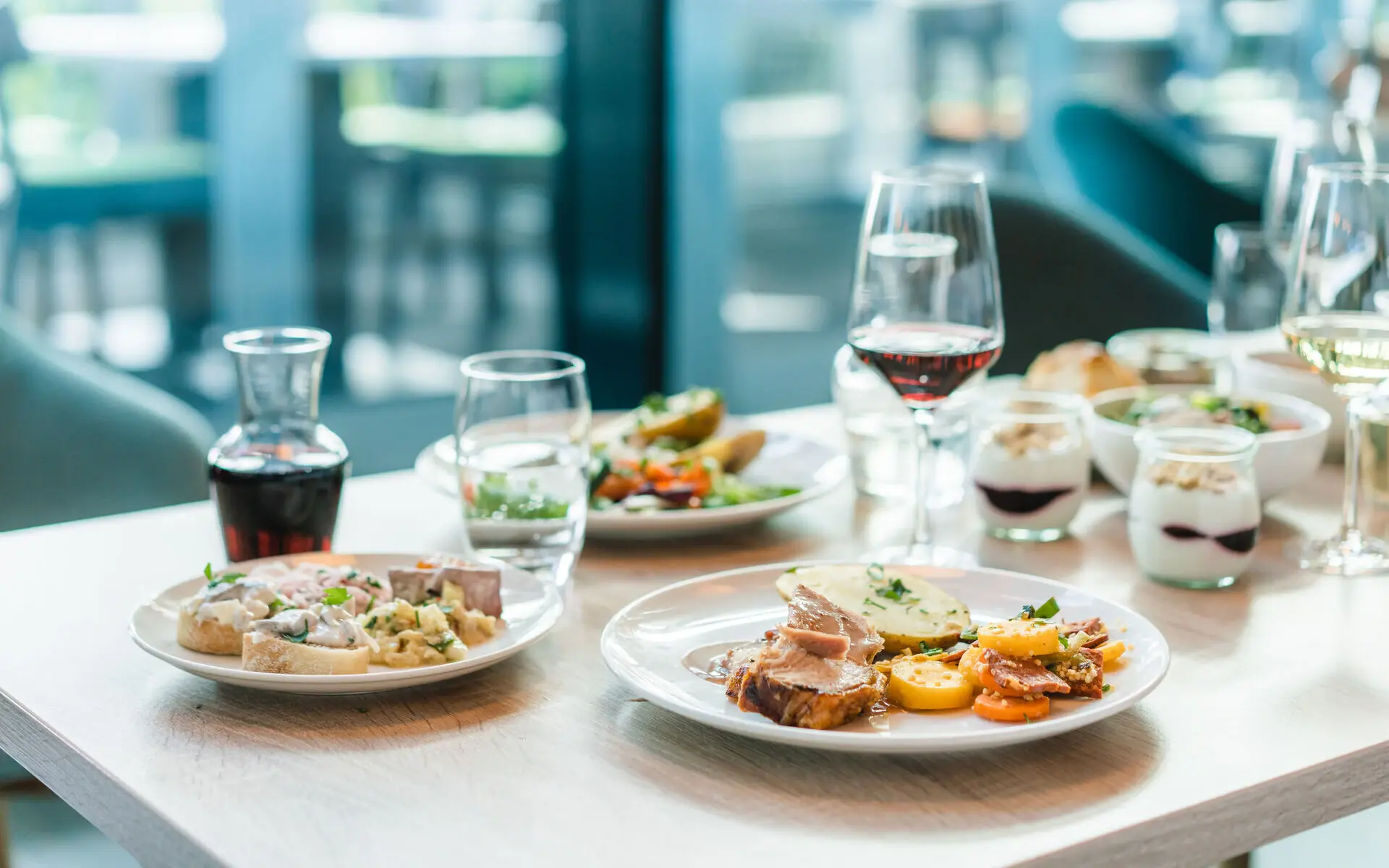 Abendessen aja Travemünde Ein appetitlich gedeckter Tisch mit warmen Speisen von einem Buffet sowie Rotwein und kleinen Nachtischgläsern mit Quark und roter Sauce.