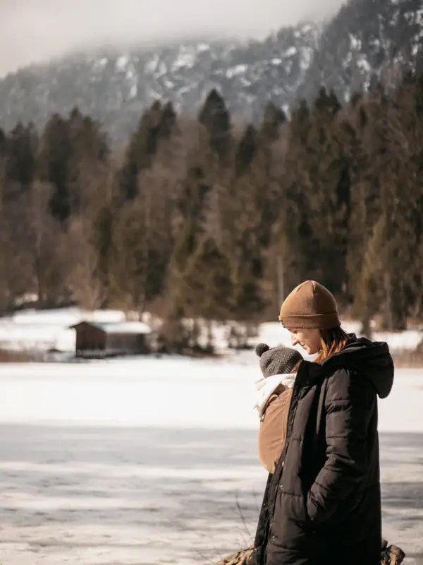 Winter in den Bergen Eine Frau hält ein Baby in einem verschneiten Gebiet.