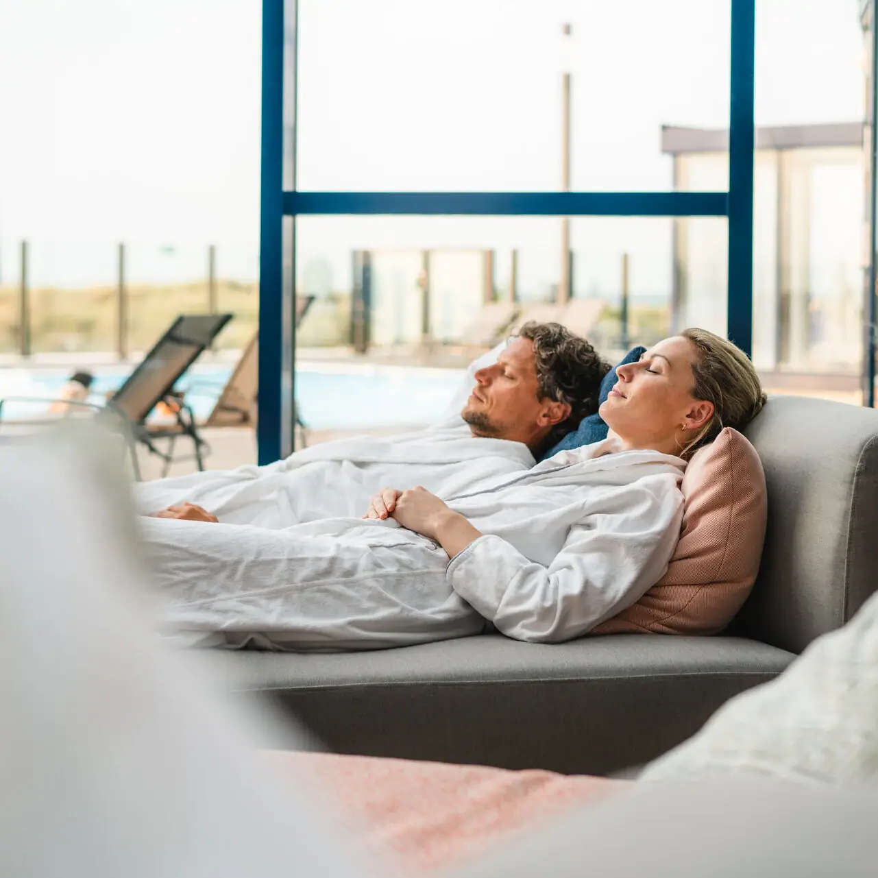 DaySPA im aja Warnemünde Ein Mann und eine Frau liegen auf einer Couch im Wellnessbereich.