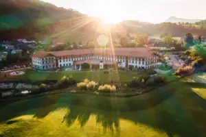 aja Ruhpolding Großes Gebäude mit großem Rasen und Parkplatz im Vordergrund.