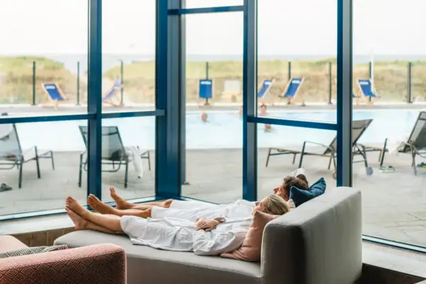 Ruhebereich im aja Warnemünde Ein Paar liegt auf einem Sofa.