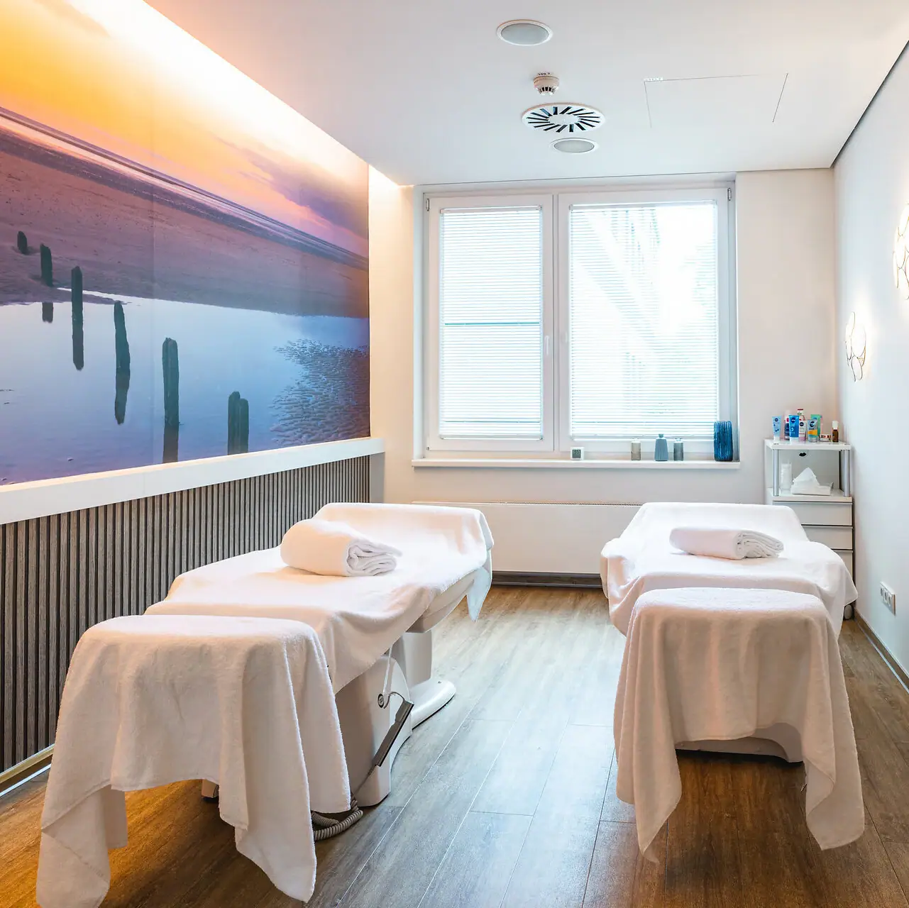 Anwendungsraum Ein Zimmer mit Betten und einem Gemälde an der Wand.