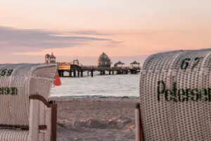 Seebrücke Ein Strandkorb am Strand mit einem Pier im Hintergrund.