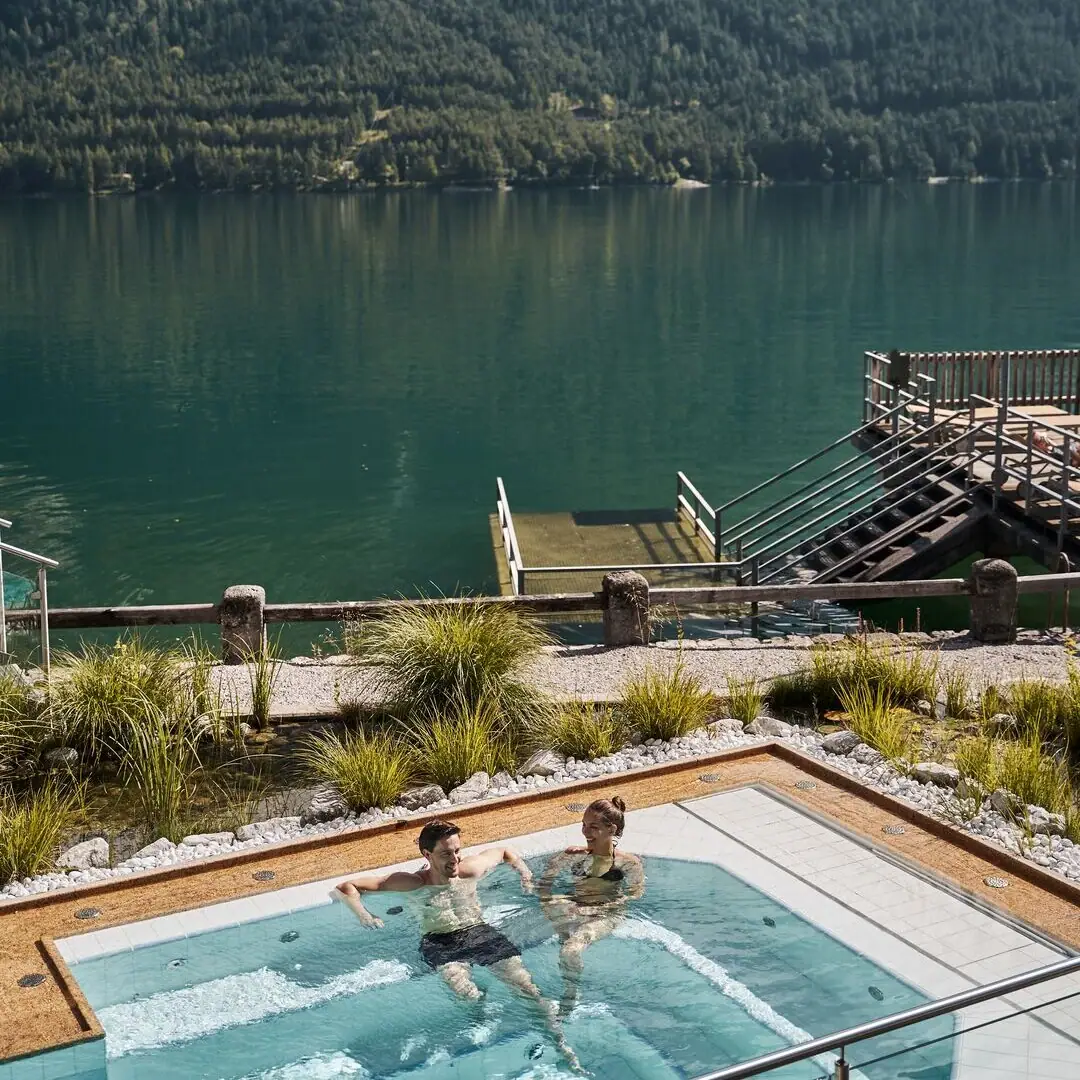 Whirlpool Menschen in einem Schwimmbecken mit einem Gewässer und Bergen im Hintergrund